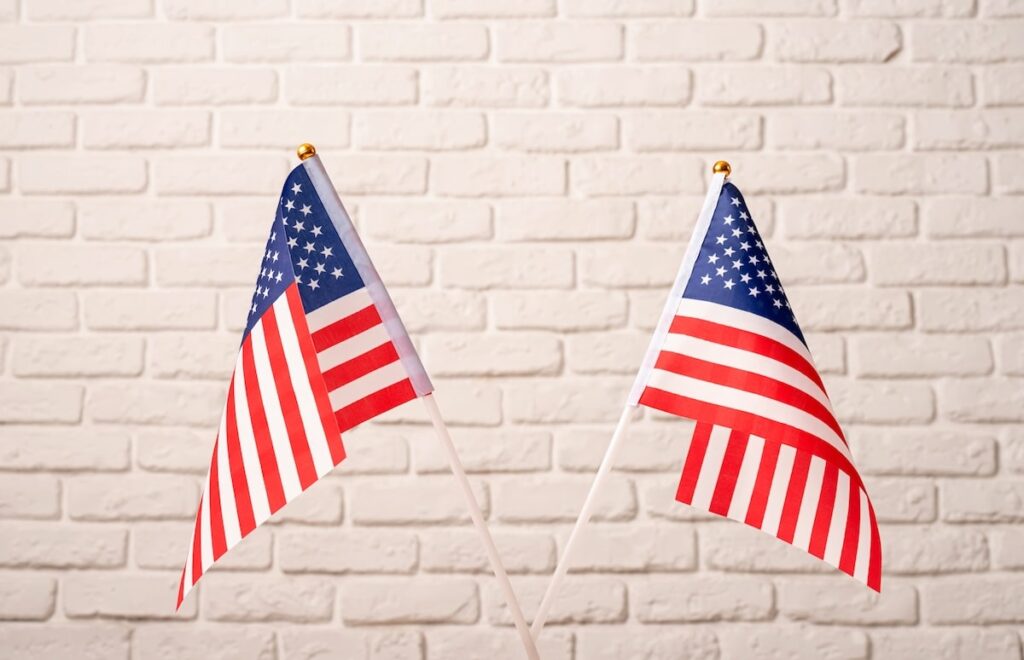 Dwie flagi amerykańskie na tle białej ściany