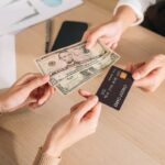 Osoba trzymająca gotówkę i kartę kredytową – wybór najlepszego rachunku bankowego dla ochrony kapitału przed wojną