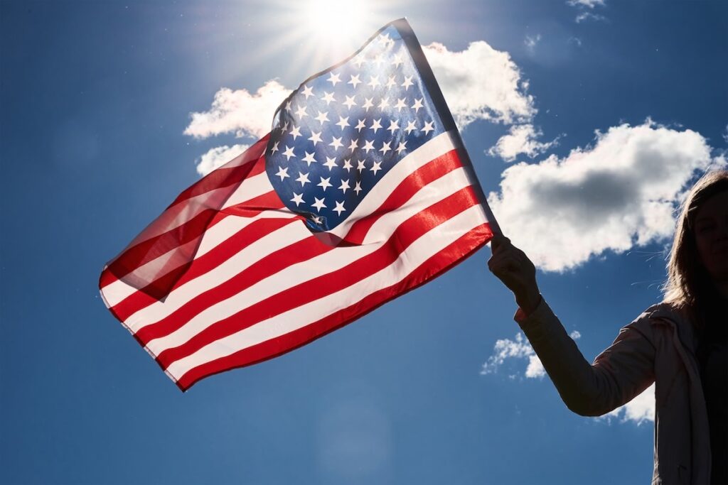 woman holds usa flag against blue sky
