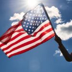 woman holds usa flag against blue sky