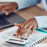Osoba obliczająca podatek estoński CIT na kalkulatorze przy biurku z dokumentami finansowymi